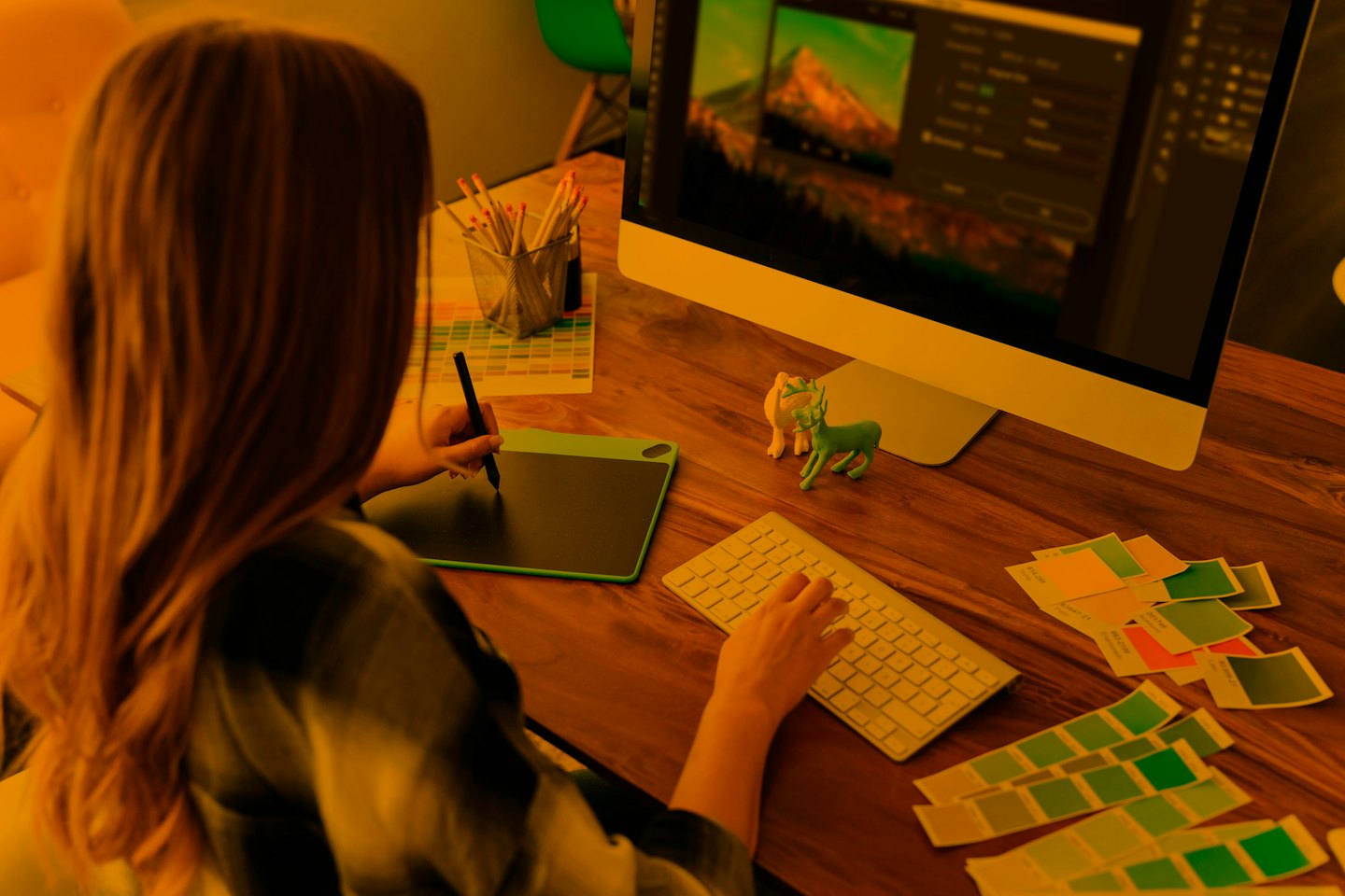 Diseñador gráfico edita imagen en computadora con tableta y teclado.