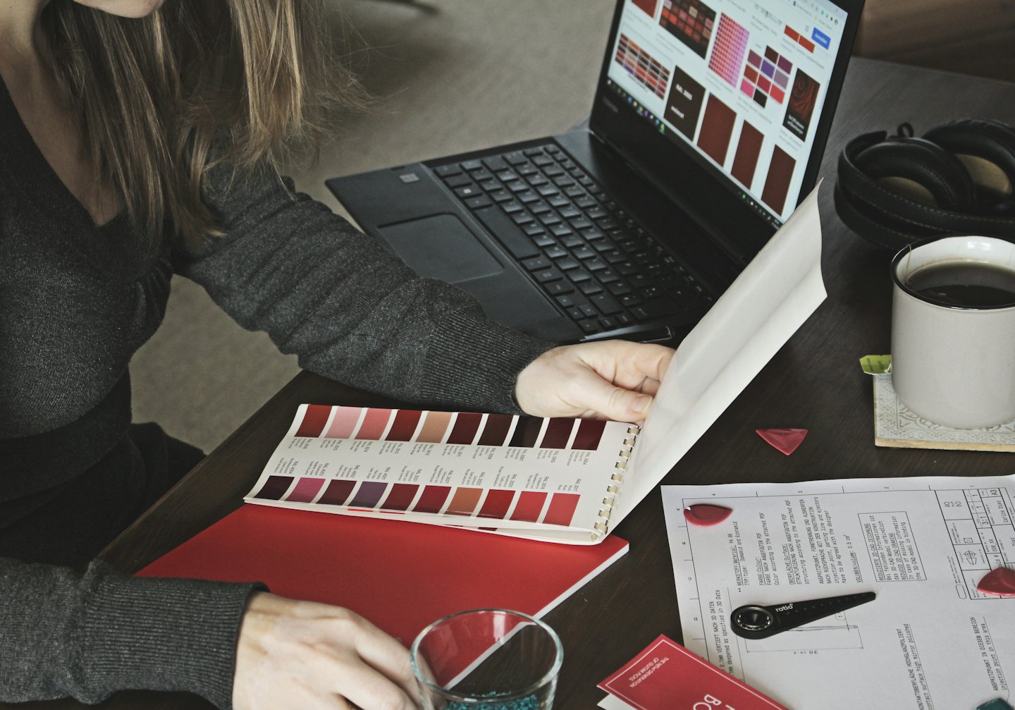 Diseñador revisa muestras de color en una laptop y en un libro.